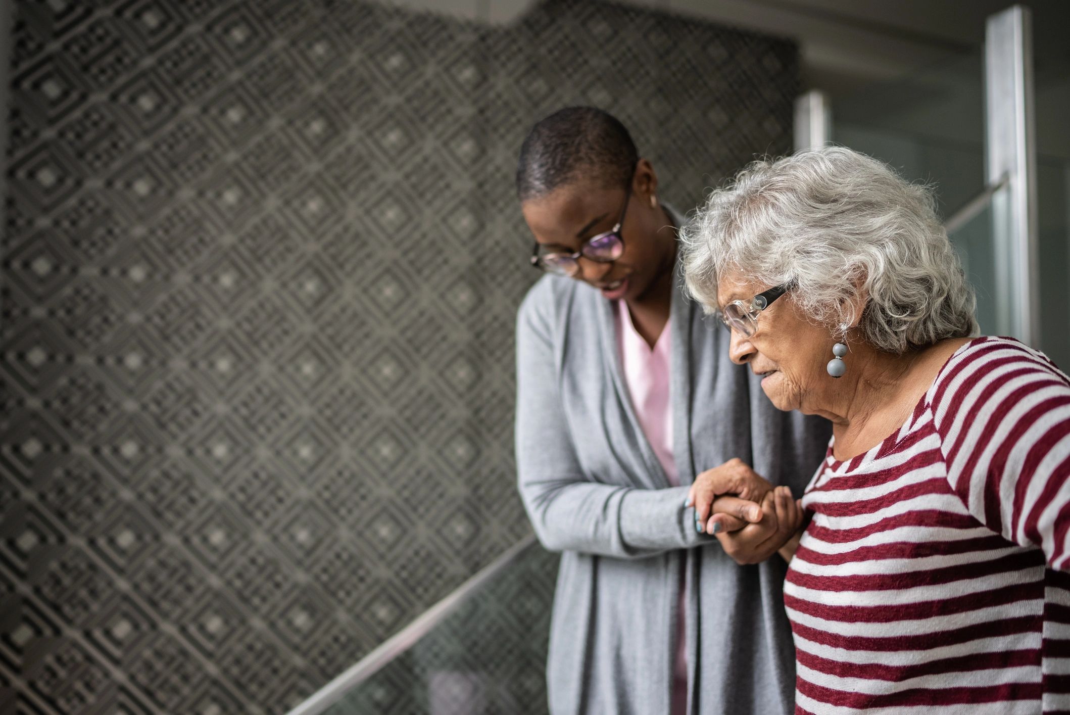 Caregiver helping a senior woman walk up stairs safely