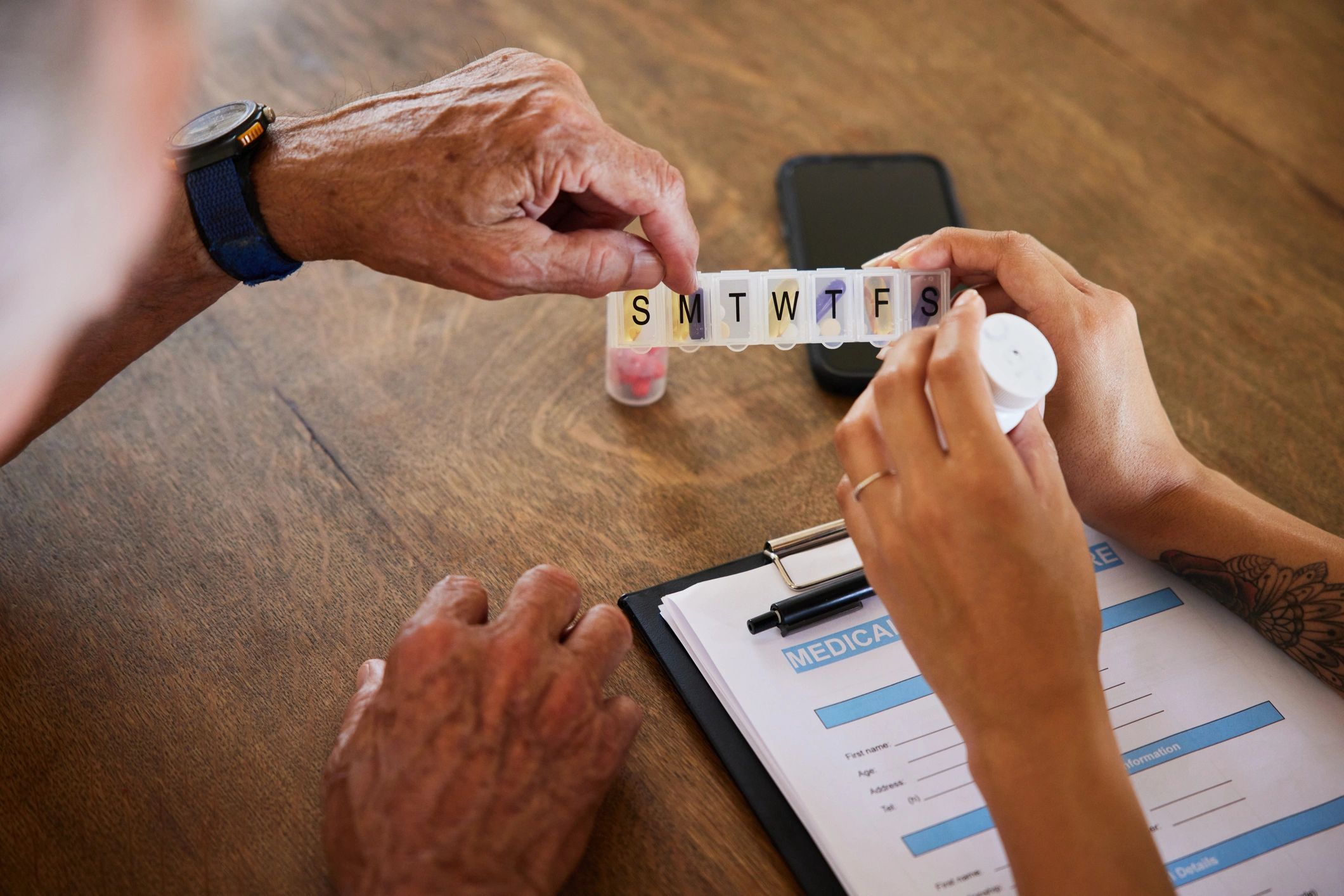 Caregiver and senior discussing medication at a table