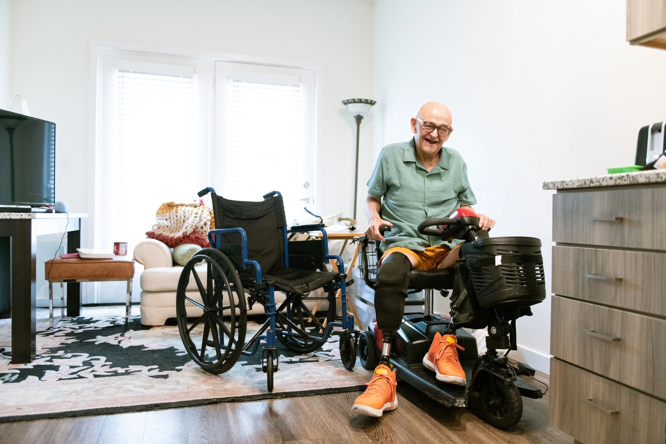 Older adult seated on a mobility scooter in an apartment hallway