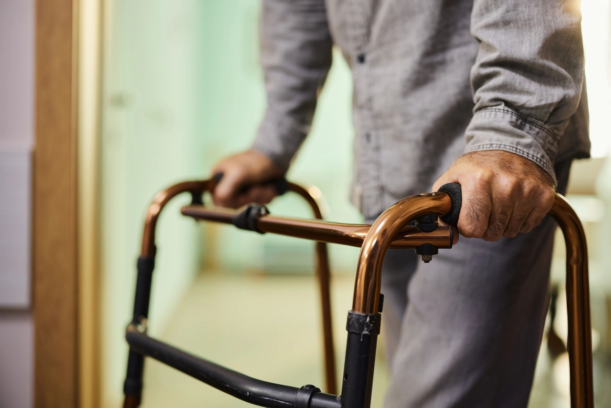 Close up of unrecognizable man using walker in hospital.