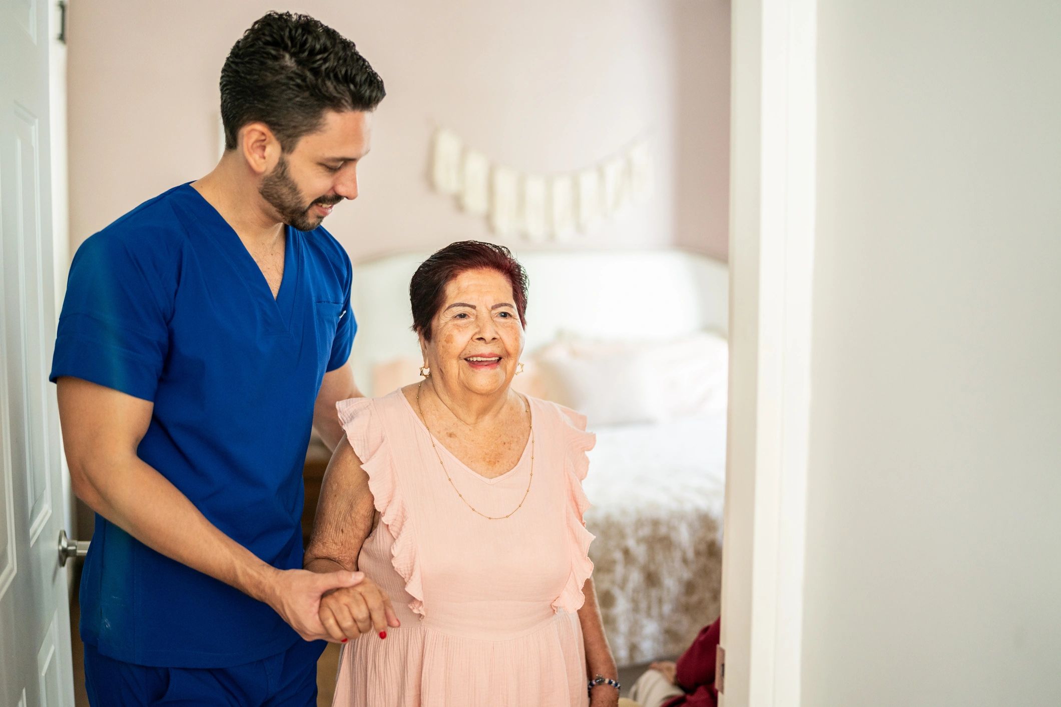 Caregiver supporting a senior woman walking at home