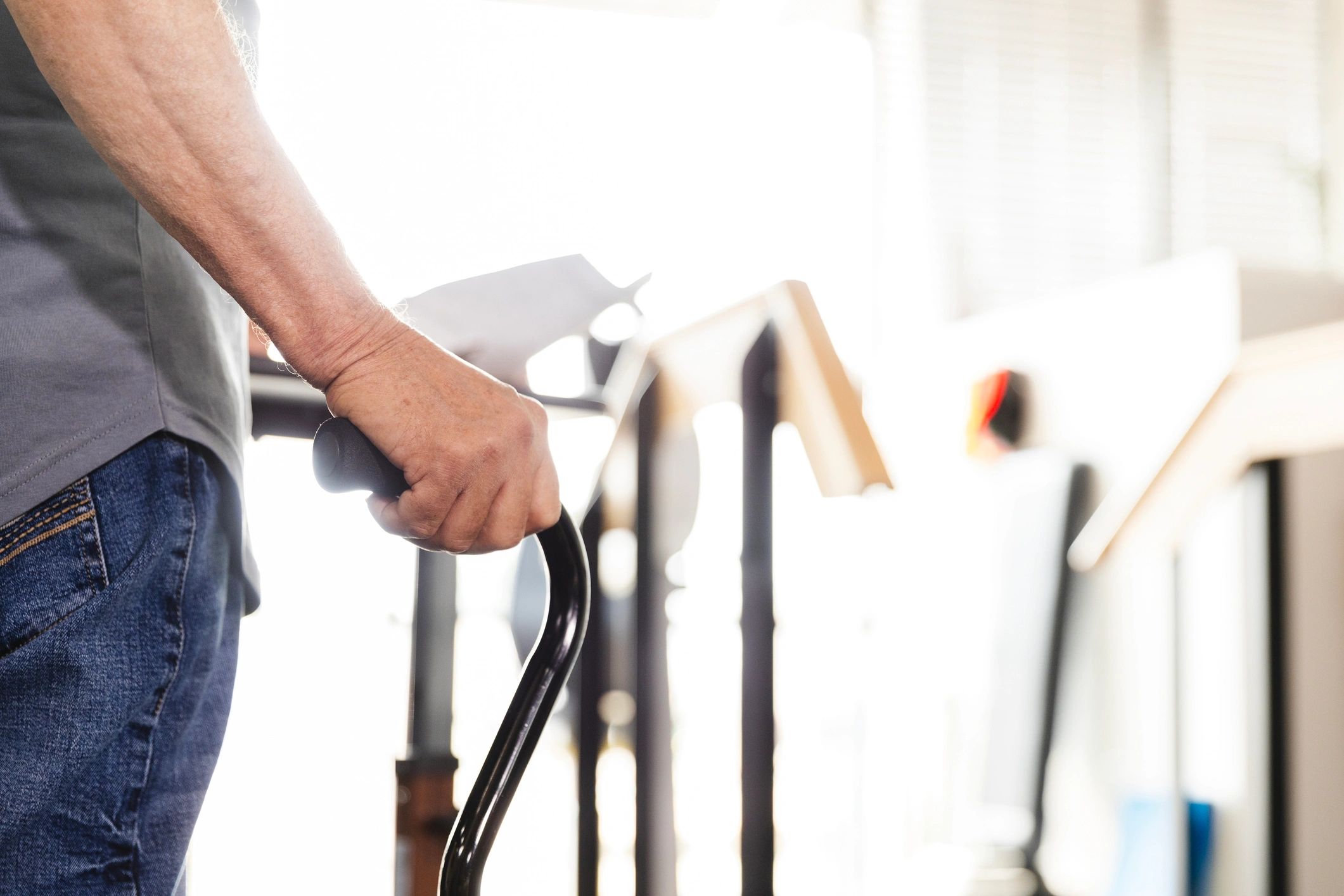 Close up photo of unrecognizable male using a walking cane during his therapy appointment