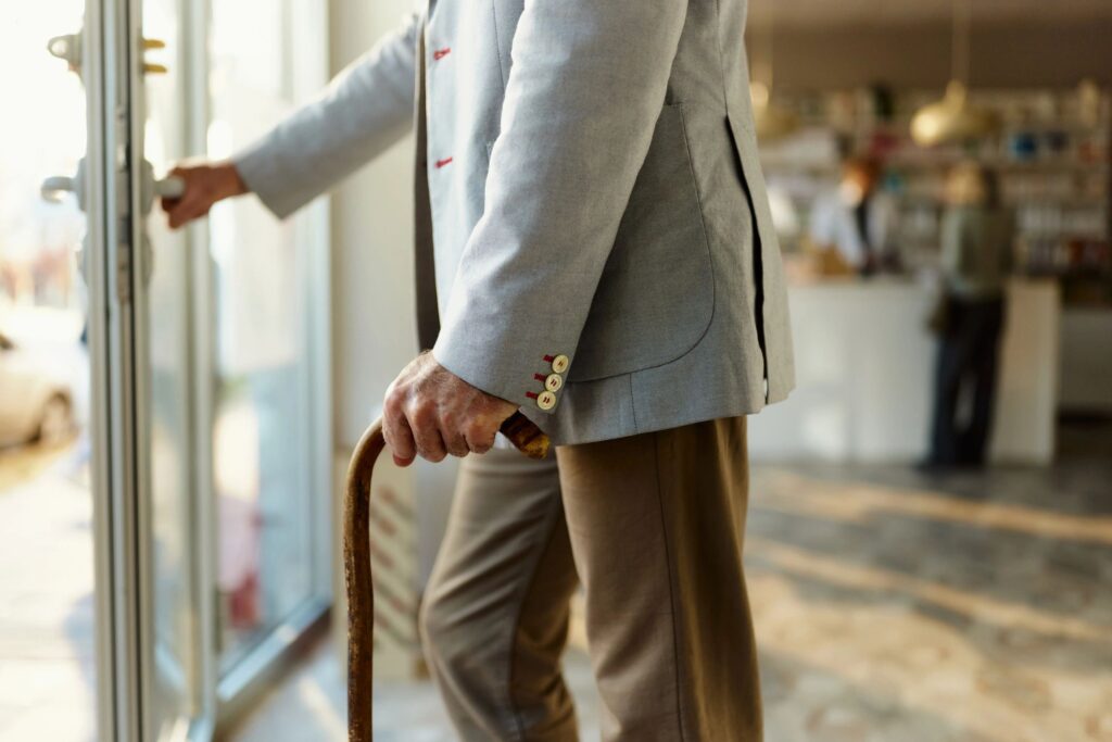 Close up of senior man using walking cane while leaving the store.
